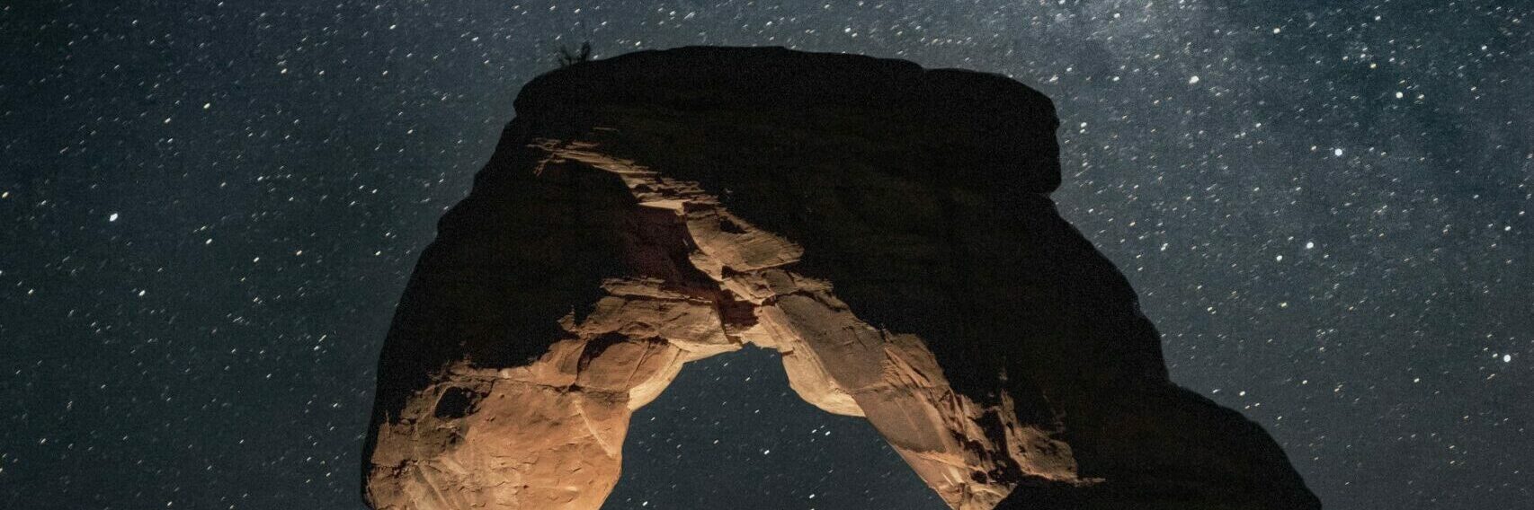 milky way galaxy above a rock formation